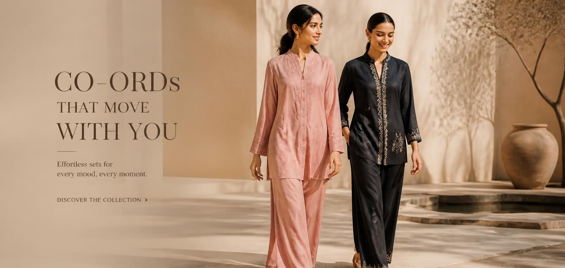 Two models in rose and ink co-ord sets walking through a sunlit courtyard